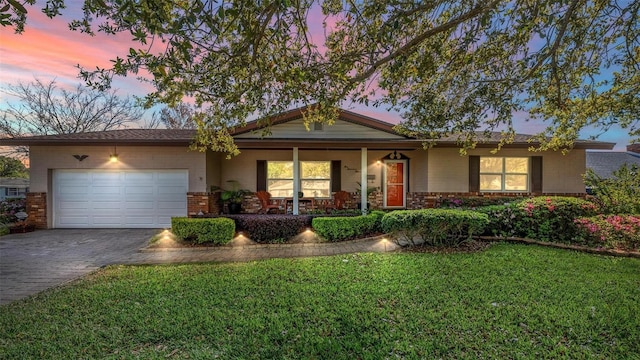 ranch-style house featuring driveway, a porch, a yard, a garage, and brick siding