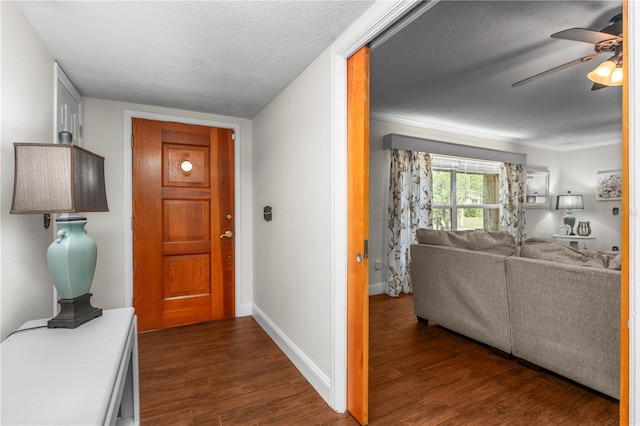 foyer entrance featuring baseboards, a textured ceiling, dark wood-type flooring, and ceiling fan