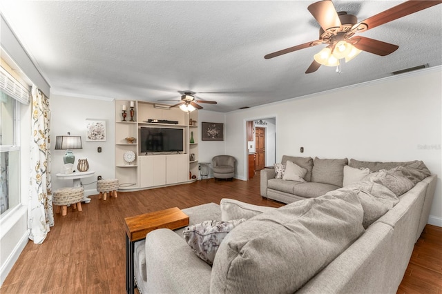 living room featuring wood finished floors, baseboards, a ceiling fan, visible vents, and a textured ceiling