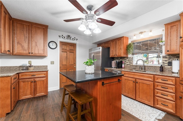 kitchen with a sink, tasteful backsplash, dark wood finished floors, freestanding refrigerator, and ceiling fan