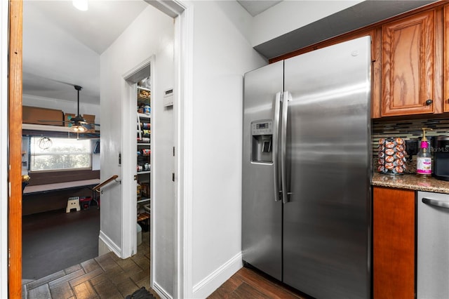 kitchen featuring backsplash, baseboards, ceiling fan, brown cabinetry, and stainless steel appliances