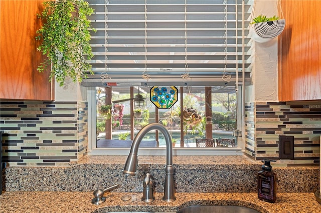 room details featuring decorative backsplash, stone countertops, and a sink