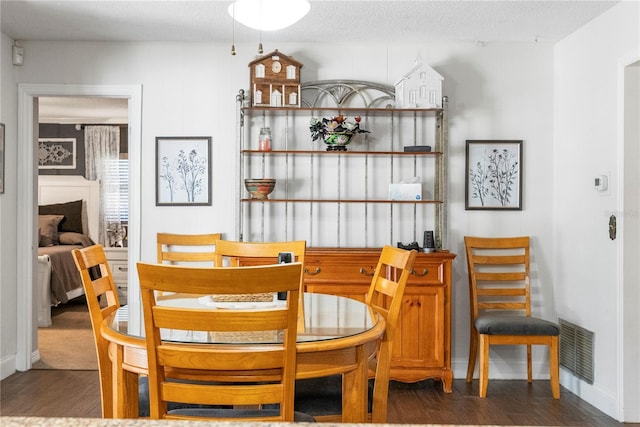 dining area featuring visible vents, baseboards, a textured ceiling, and wood finished floors