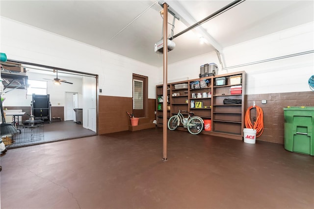 garage with concrete block wall, a garage door opener, and ceiling fan