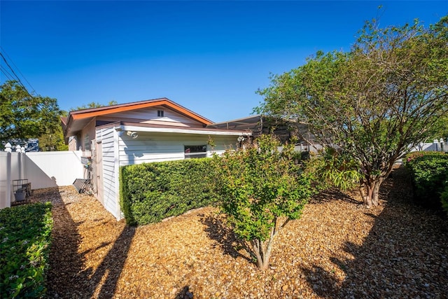 view of home's exterior featuring glass enclosure and fence