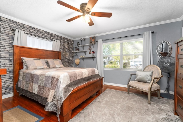 bedroom with brick wall, a textured ceiling, wood finished floors, and ornamental molding