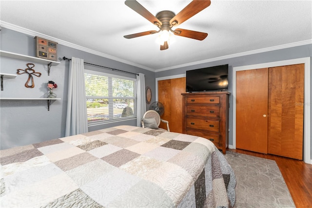 bedroom with a ceiling fan, crown molding, wood finished floors, and two closets