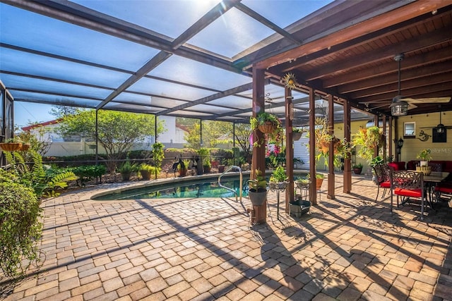 view of swimming pool featuring glass enclosure, a patio, a fenced in pool, and ceiling fan