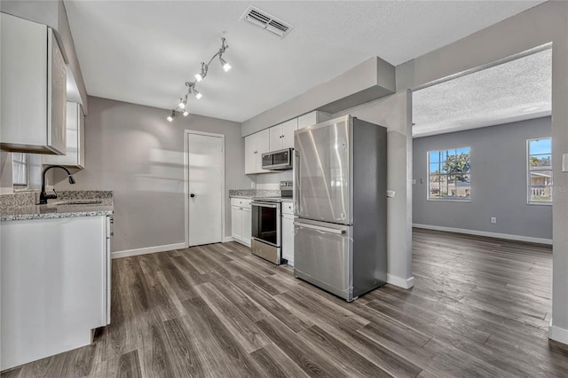 kitchen with visible vents, dark wood finished floors, a sink, appliances with stainless steel finishes, and white cabinetry