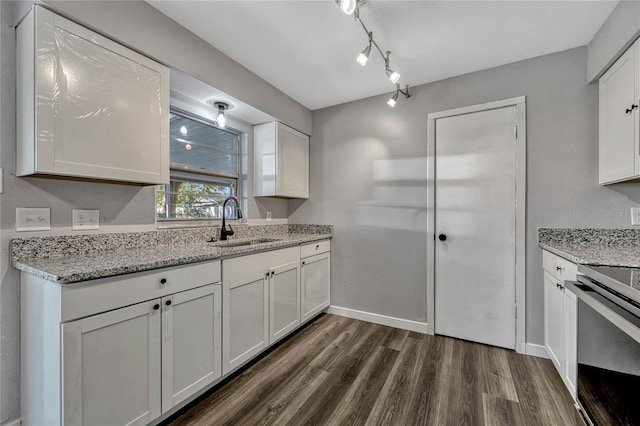 kitchen with a sink, stove, dark wood finished floors, and white cabinetry