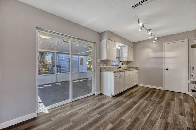 kitchen with a sink, visible vents, dark wood-type flooring, and white cabinetry