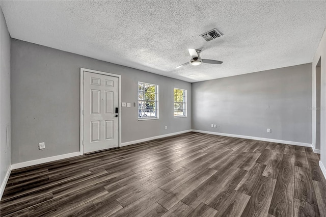 empty room with visible vents, baseboards, dark wood-type flooring, and a ceiling fan