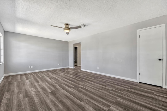 empty room with visible vents, baseboards, dark wood-style floors, and a ceiling fan