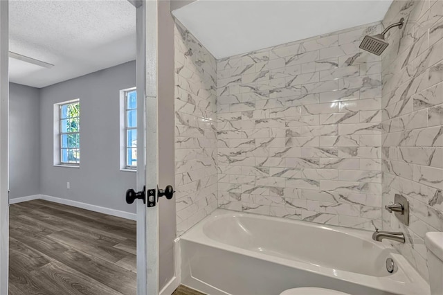 bathroom with a textured ceiling, shower / tub combination, baseboards, and wood finished floors