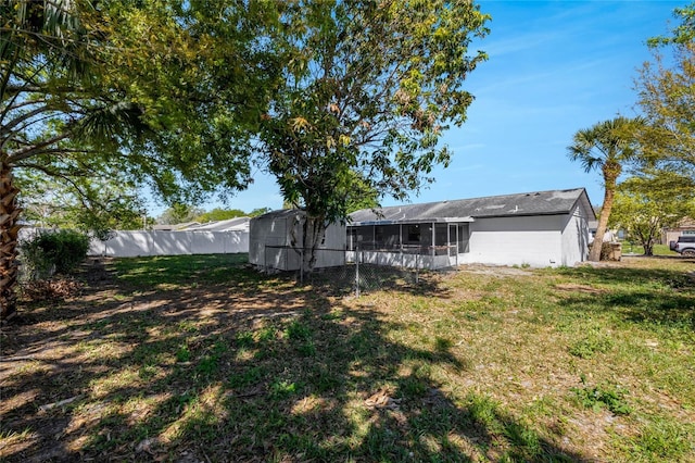 view of yard featuring an outbuilding, fence, and a sunroom