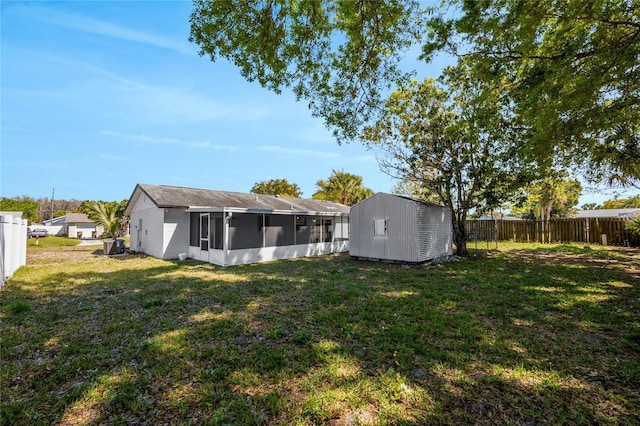 view of yard featuring a storage shed, a sunroom, fence, and an outdoor structure