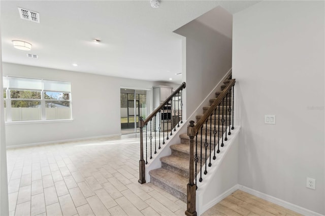 stairs with wood finished floors, visible vents, and baseboards