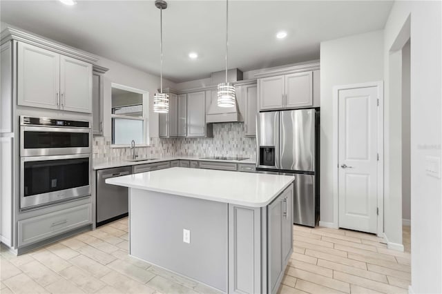 kitchen featuring a sink, wall chimney exhaust hood, gray cabinets, and stainless steel appliances