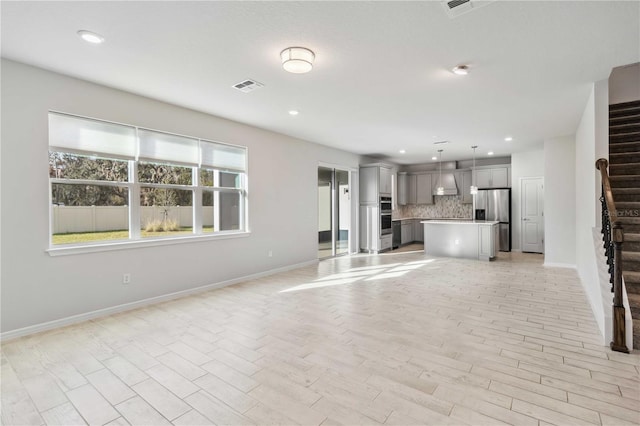 unfurnished living room featuring recessed lighting, visible vents, baseboards, and stairs