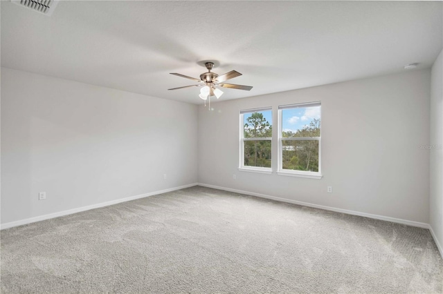 unfurnished room with visible vents, a ceiling fan, baseboards, and carpet floors