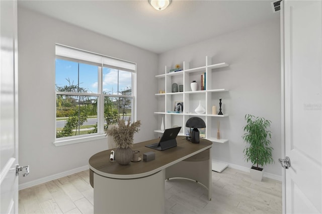 home office with light wood-style flooring, baseboards, and visible vents
