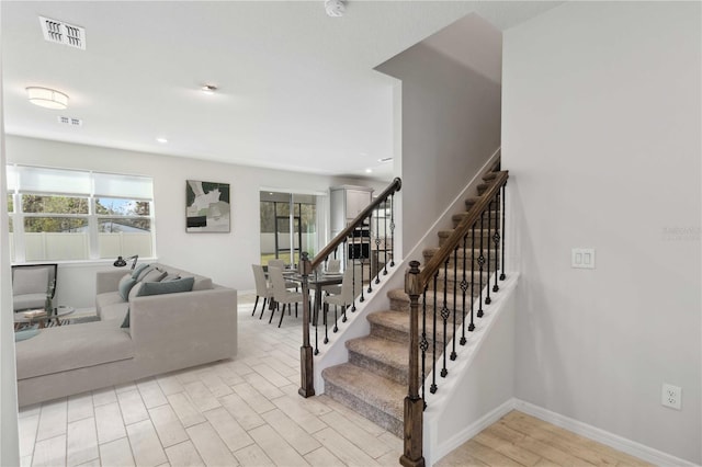 stairway with wood finished floors, visible vents, and baseboards