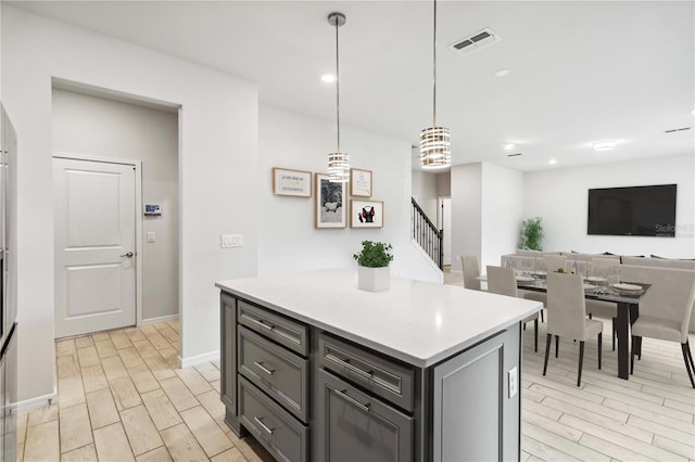 kitchen with visible vents, a kitchen island, wood tiled floor, light countertops, and gray cabinets