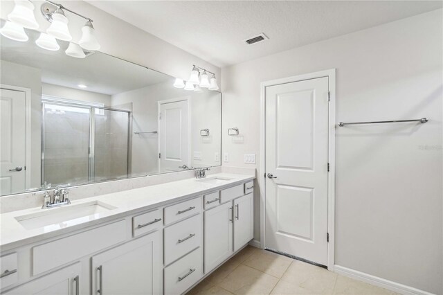 bathroom with tile patterned floors, a shower stall, double vanity, and a sink