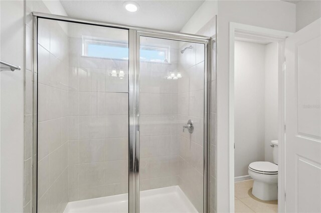 bathroom featuring tile patterned floors, a stall shower, and toilet