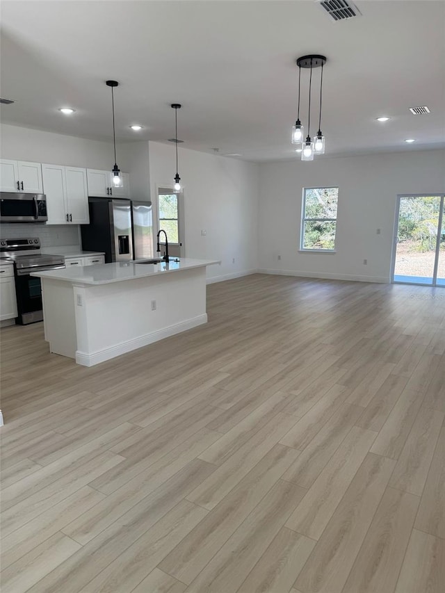 kitchen with a sink, light countertops, open floor plan, and stainless steel appliances