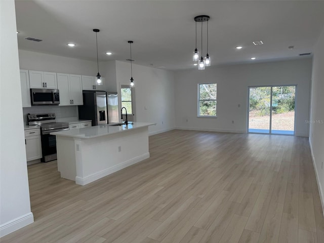 kitchen with visible vents, light wood-style flooring, a sink, decorative backsplash, and appliances with stainless steel finishes