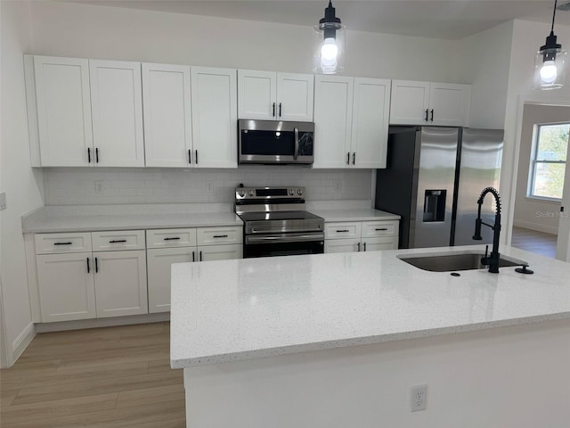 kitchen with a sink, backsplash, appliances with stainless steel finishes, and white cabinetry