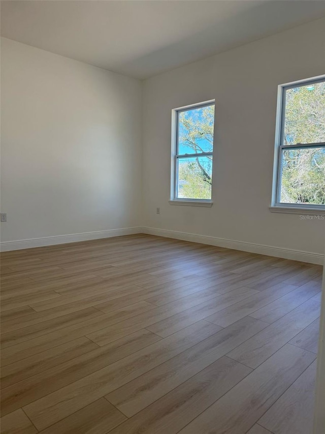 spare room with a healthy amount of sunlight, baseboards, and wood finished floors