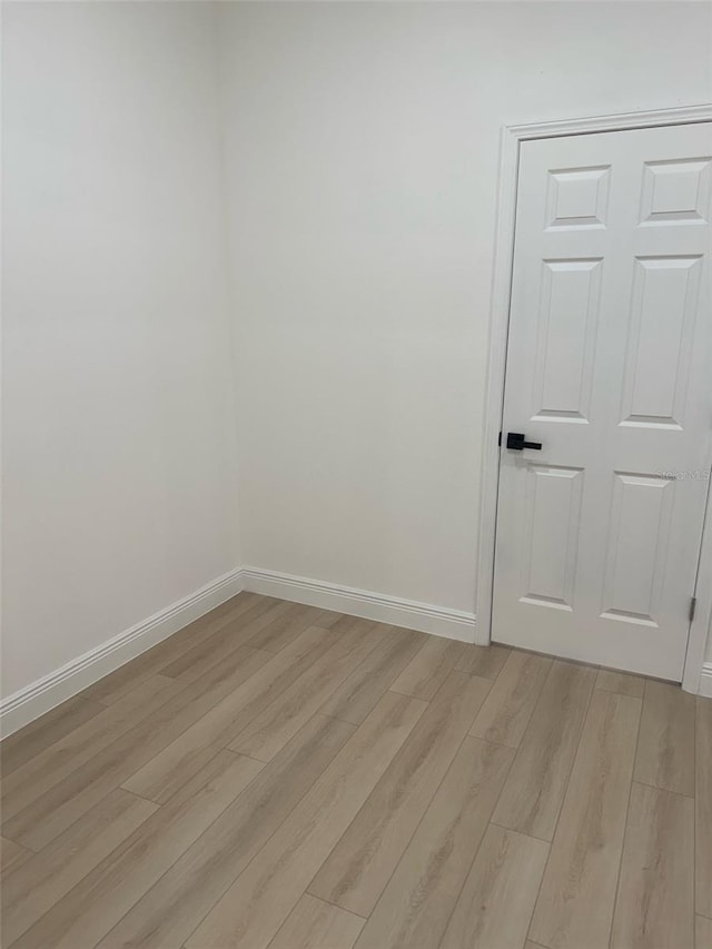 spare room featuring light wood-type flooring and baseboards