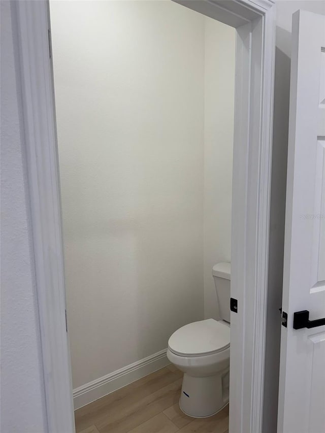 bathroom with baseboards, toilet, and wood finished floors