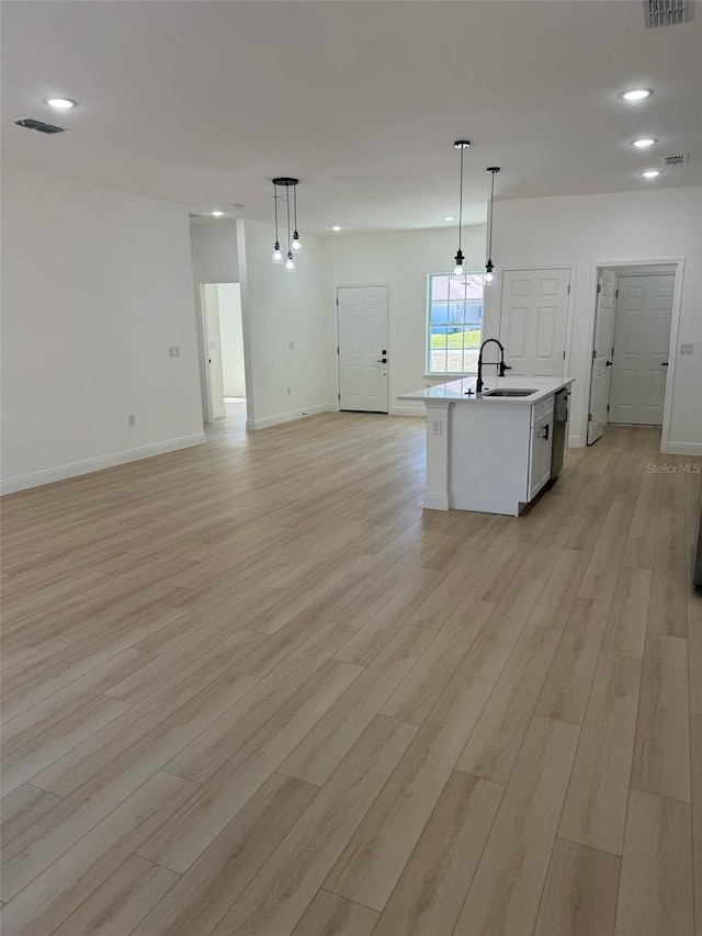 kitchen with visible vents, light wood finished floors, a sink, stainless steel dishwasher, and open floor plan