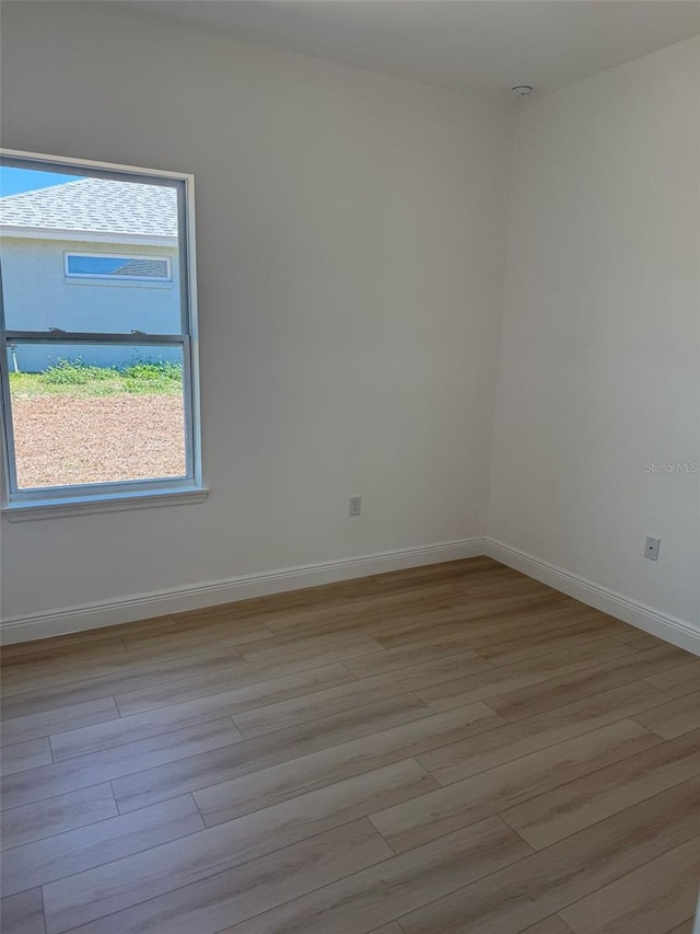 spare room with baseboards, a healthy amount of sunlight, and wood finished floors