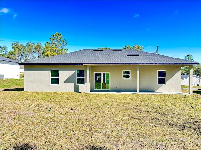 back of house featuring stucco siding, a yard, and roof with shingles