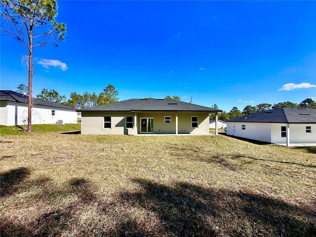 rear view of house featuring a yard and stucco siding