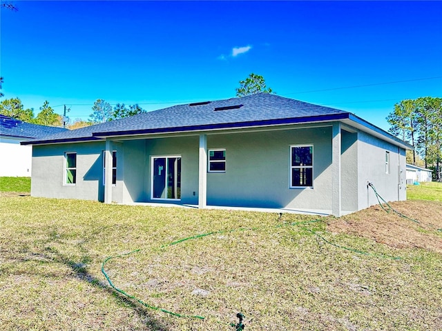 back of property with a lawn, roof with shingles, and stucco siding