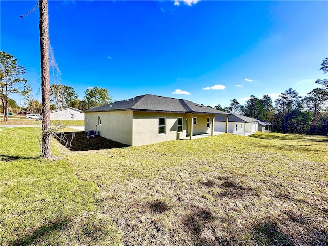 back of house with a lawn, cooling unit, and stucco siding