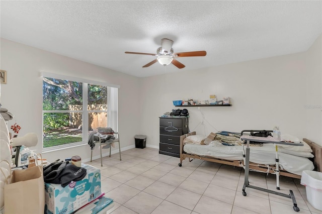 interior space featuring light tile patterned floors, baseboards, a textured ceiling, and a ceiling fan