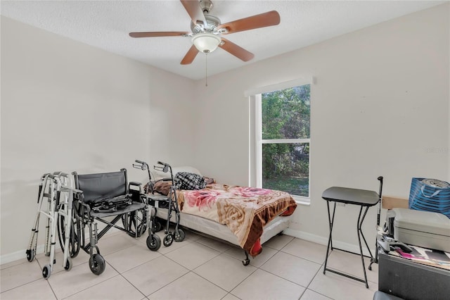 bedroom featuring light tile patterned floors, ceiling fan, a textured ceiling, and baseboards