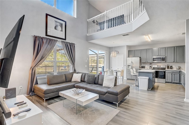 1028 Orange Cosmos Blvd, Davenport, FL 33837 - living area featuring light wood-style floors, a towering ceiling, and a chandelier
