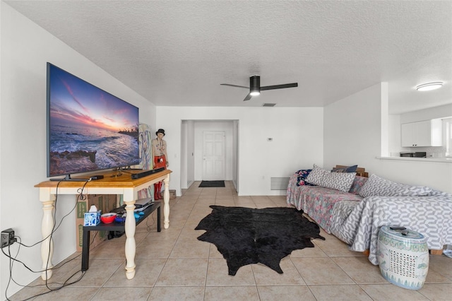 living area with light tile patterned floors, visible vents, a textured ceiling, and ceiling fan