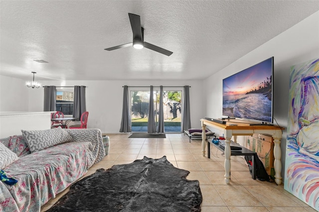 living area featuring light tile patterned floors, ceiling fan with notable chandelier, and a textured ceiling