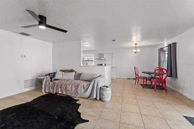 living area with light tile patterned floors, ceiling fan with notable chandelier, visible vents, and a textured ceiling