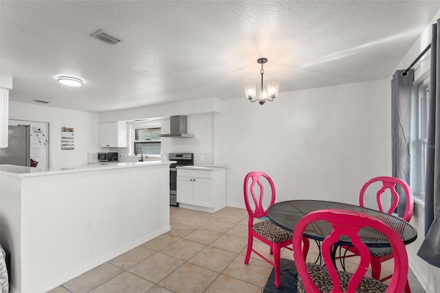 kitchen featuring visible vents, appliances with stainless steel finishes, an inviting chandelier, white cabinetry, and wall chimney exhaust hood