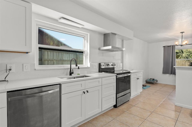 kitchen with appliances with stainless steel finishes, light tile patterned flooring, white cabinetry, wall chimney exhaust hood, and a sink