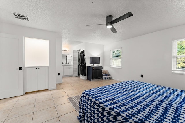 bedroom with light tile patterned flooring, visible vents, a textured ceiling, and ceiling fan